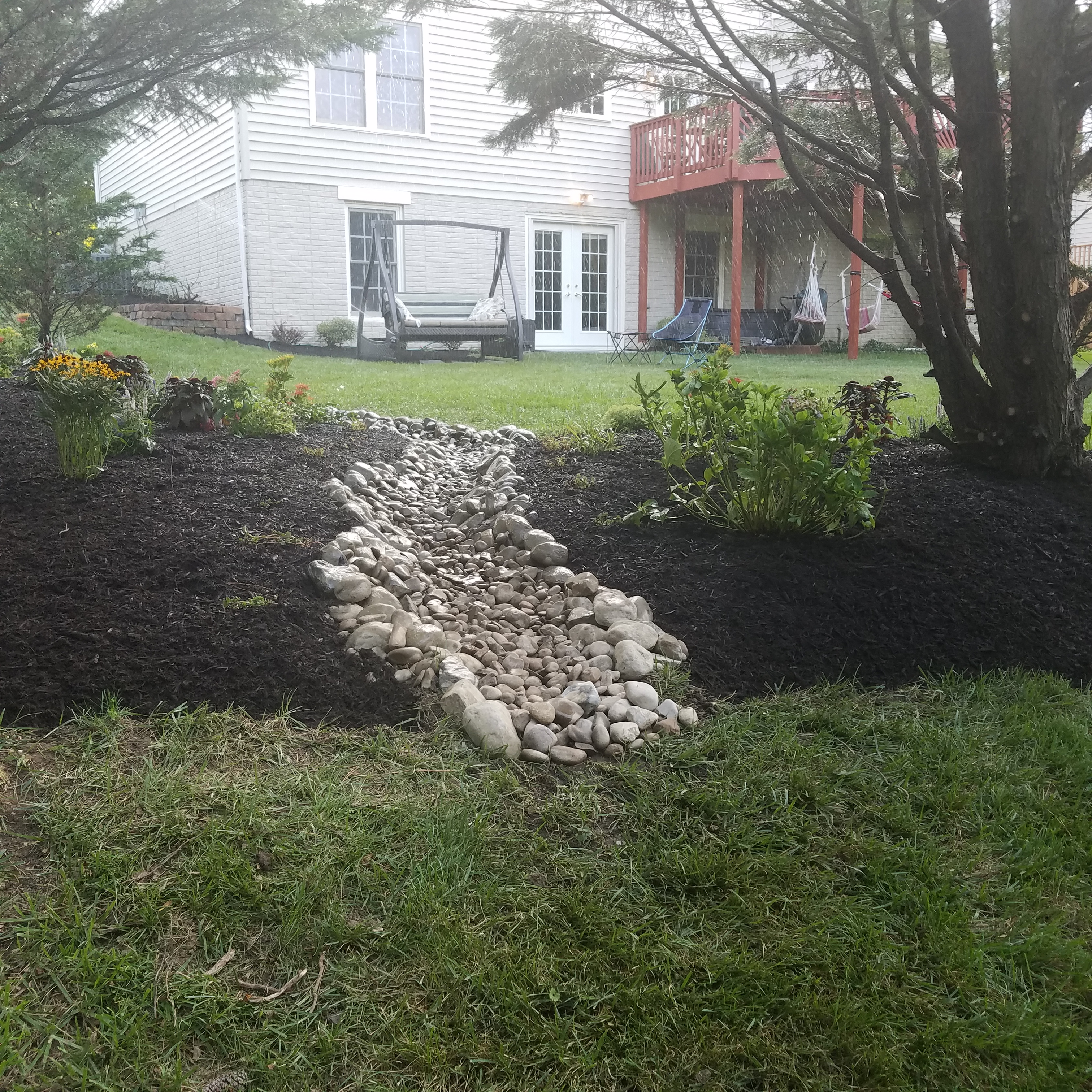 Gorgeous stone water way splitting two gardens in a residential backyard